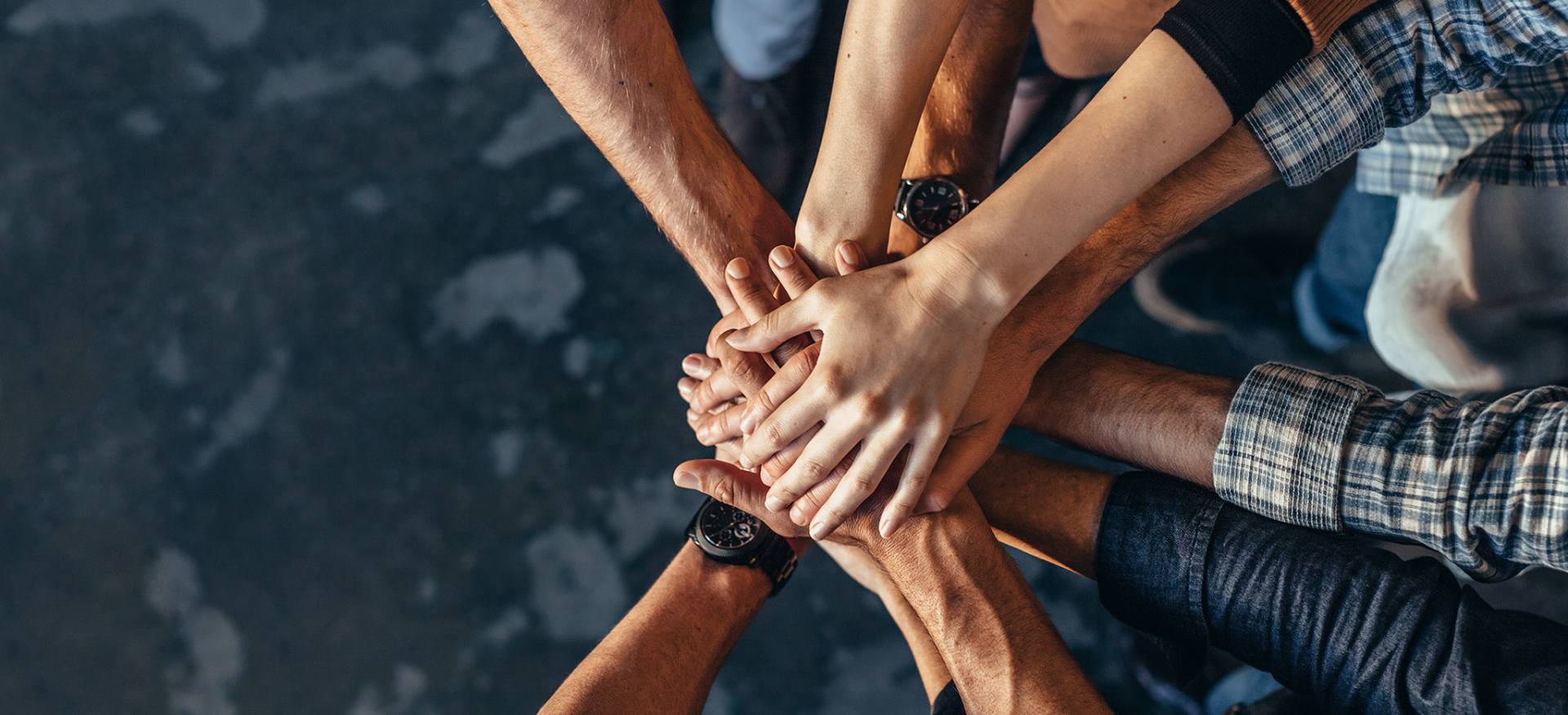 Grupa ubezpieczonych osób w geście solidarności układa dłonie jedna na drugiej