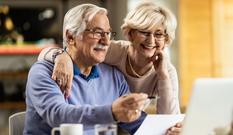 Starszy mężczyzna i kobieta szczęśliwie patrzą na umowę na ubezpieczenie na życie.